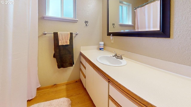 bathroom featuring vanity, plenty of natural light, wood finished floors, and a textured wall