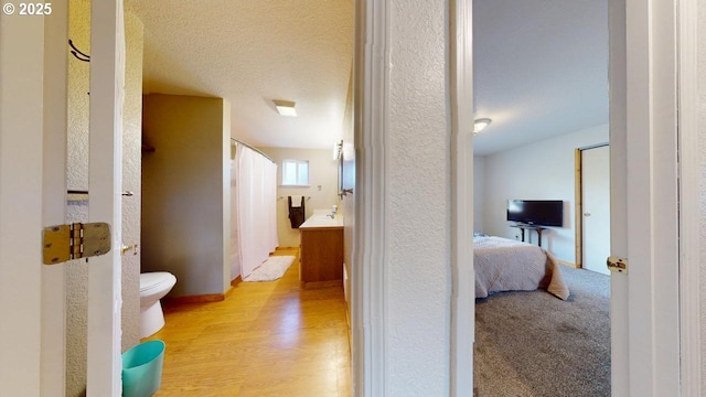 corridor featuring a textured ceiling and light wood finished floors