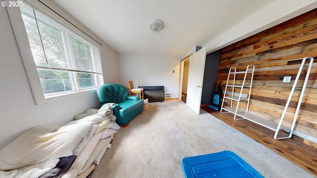 sitting room with visible vents, wooden walls, and wood finished floors