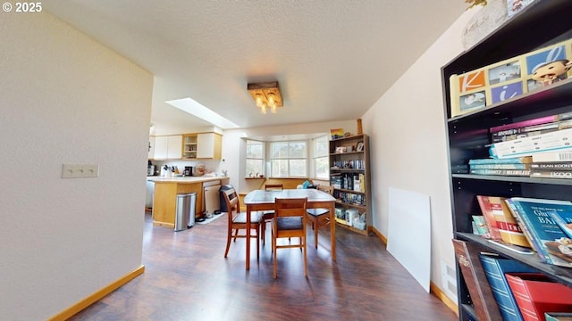 dining area with a skylight, a textured ceiling, and baseboards