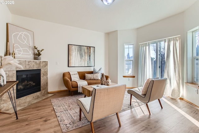 living area with a tiled fireplace and light hardwood / wood-style floors