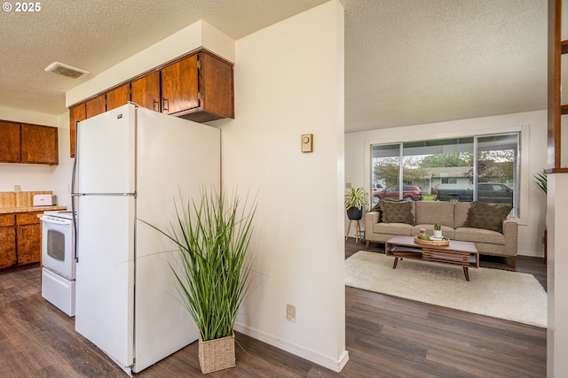 kitchen featuring a textured ceiling, brown cabinetry, white appliances, dark wood-style flooring, and visible vents