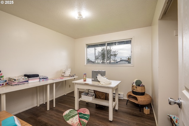 office area featuring baseboard heating, dark wood finished floors, and a textured ceiling