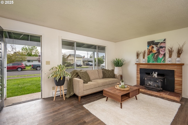 living room featuring a baseboard radiator, dark wood-style flooring, a textured ceiling, and a healthy amount of sunlight