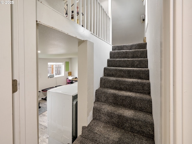 stairs with hardwood / wood-style flooring and washer / dryer