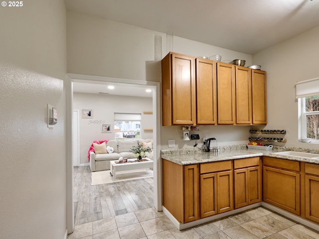 kitchen with light stone counters, sink, and light hardwood / wood-style flooring