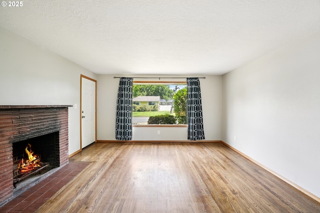 3259 SE 176th Pl, Portland, OR 97236 - unfurnished living room with wood finished floors, a fireplace, and a textured ceiling