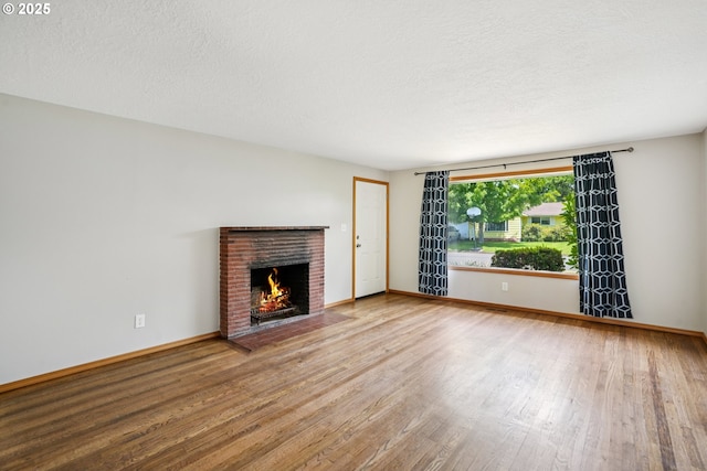3259 SE 176th Pl, Portland, OR 97236 - unfurnished living room with wood finished floors, a fireplace, and a textured ceiling