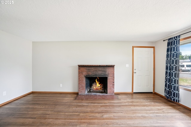 3259 SE 176th Pl, Portland, OR 97236 - unfurnished living room featuring wood finished floors, a brick fireplace, and a textured ceiling