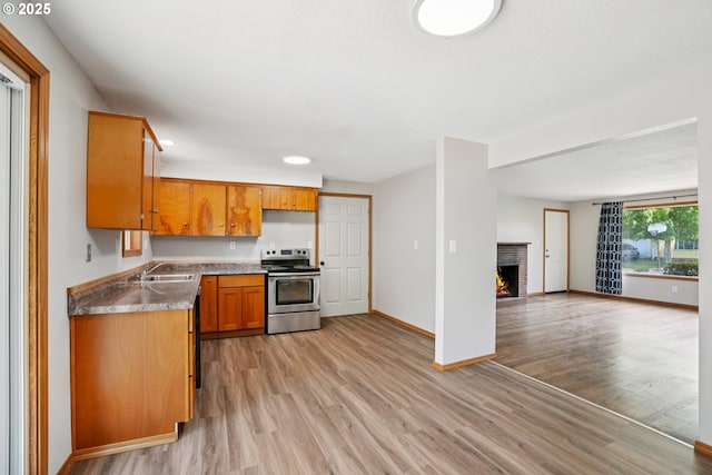 3259 SE 176th Pl, Portland, OR 97236 - kitchen with stainless steel range with electric stovetop, light wood-type flooring, brown cabinets, and open floor plan