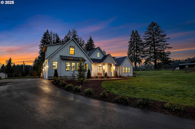 modern farmhouse style home with a yard, board and batten siding, a standing seam roof, metal roof, and fence