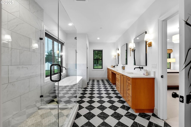 bathroom featuring double vanity, a stall shower, a freestanding bath, a sink, and recessed lighting