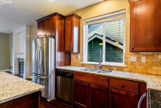 kitchen with light stone countertops, appliances with stainless steel finishes, sink, and decorative backsplash