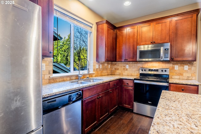 kitchen featuring dark wood-type flooring, sink, light stone counters, appliances with stainless steel finishes, and backsplash