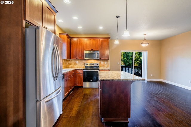 kitchen featuring light stone counters, hanging light fixtures, appliances with stainless steel finishes, a kitchen island, and backsplash