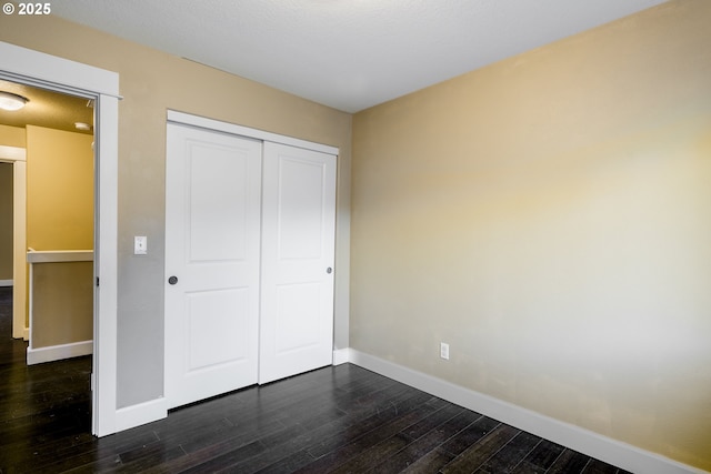 unfurnished bedroom with dark hardwood / wood-style flooring and a closet