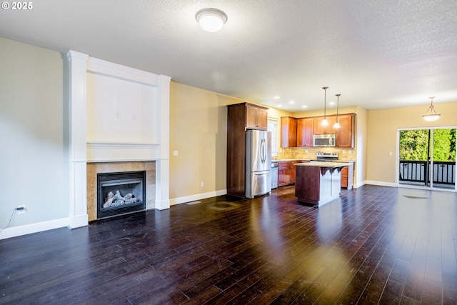 kitchen with appliances with stainless steel finishes, dark hardwood / wood-style flooring, a kitchen breakfast bar, hanging light fixtures, and a center island