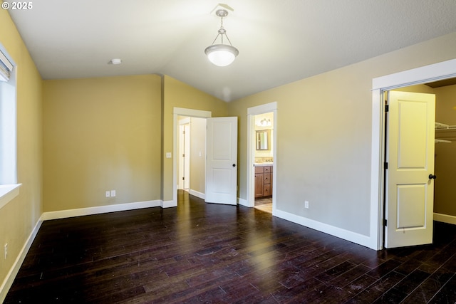 unfurnished bedroom with ensuite bathroom, dark hardwood / wood-style floors, and vaulted ceiling