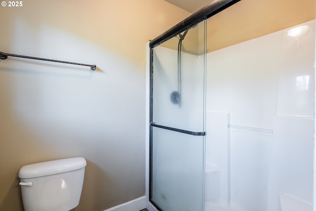 bathroom featuring a shower with shower door and toilet