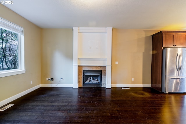 unfurnished living room with dark hardwood / wood-style flooring and a tiled fireplace