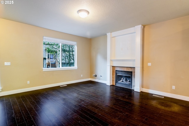 unfurnished living room with a tiled fireplace, hardwood / wood-style floors, and a textured ceiling