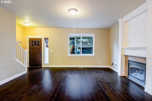 unfurnished living room featuring a tiled fireplace, dark hardwood / wood-style floors, and a textured ceiling