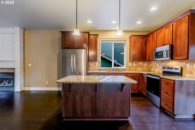 kitchen featuring stainless steel appliances, hanging light fixtures, a breakfast bar, and light stone counters