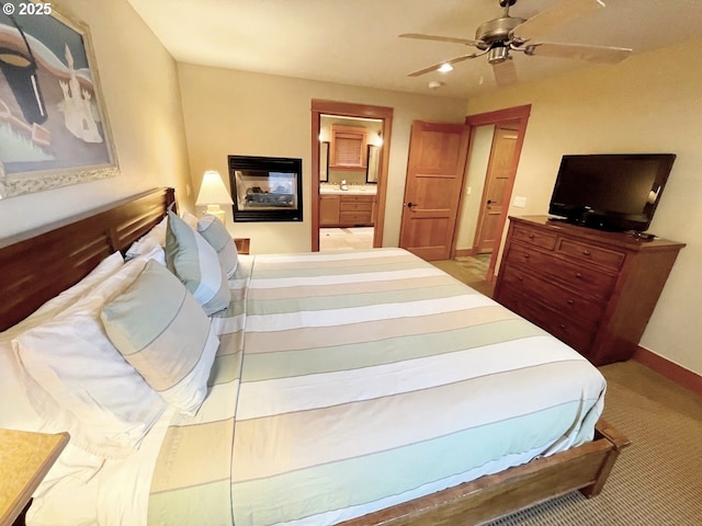 carpeted bedroom with ensuite bath and ceiling fan