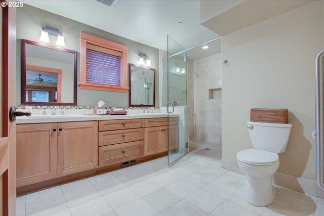 bathroom with a tile shower, ceiling fan, vanity, and toilet