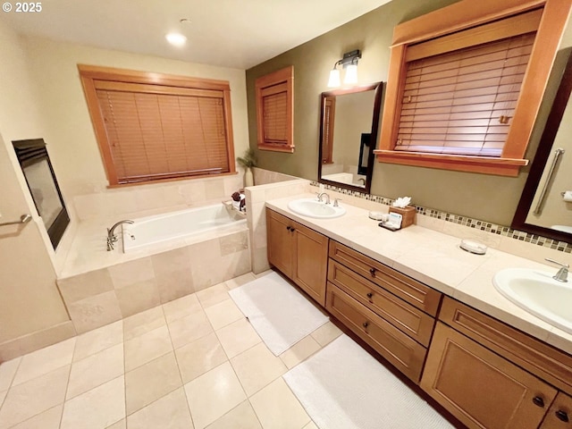 bathroom with tile patterned flooring, vanity, and tiled bath