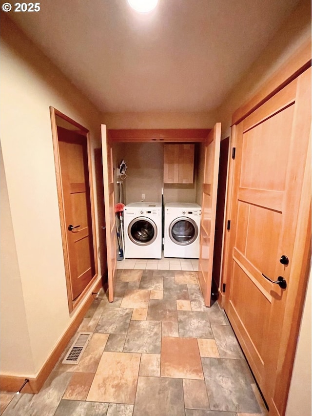 clothes washing area with cabinets and washing machine and dryer