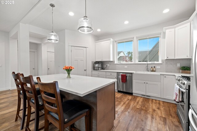 1046 SE Olive Way, Estacada, OR 97023 - kitchen featuring stainless steel appliances, wood finished floors, decorative backsplash, a breakfast bar area, and light countertops