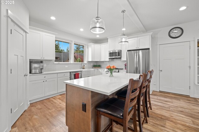 1046 SE Olive Way, Estacada, OR 97023 - kitchen with appliances with stainless steel finishes, light wood finished floors, a kitchen bar, recessed lighting, and decorative backsplash