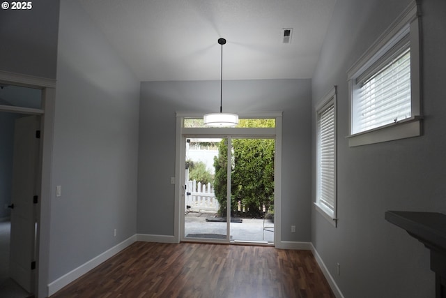 unfurnished dining area featuring vaulted ceiling and dark hardwood / wood-style floors