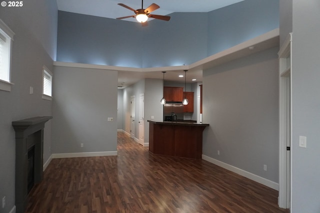 unfurnished living room featuring ceiling fan, a high ceiling, and dark hardwood / wood-style flooring