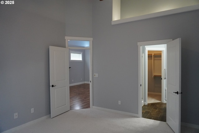 unfurnished bedroom featuring a closet, a spacious closet, and dark colored carpet