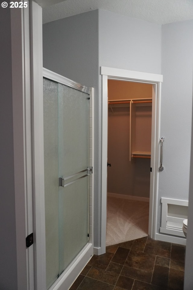 bathroom with toilet, a textured ceiling, and walk in shower