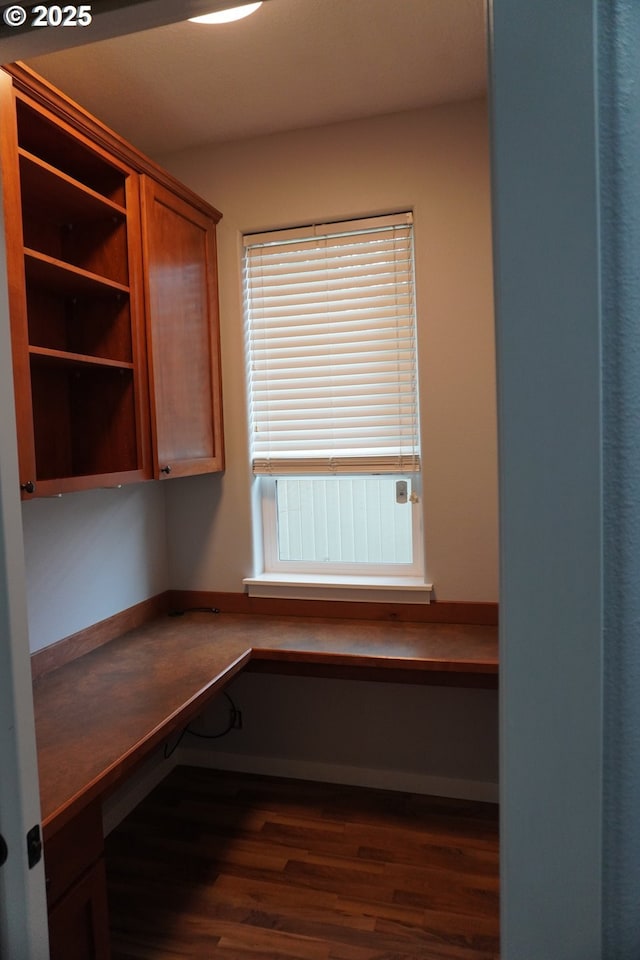 unfurnished office with dark wood-type flooring and built in desk