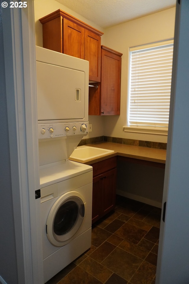 washroom with cabinets and stacked washer / drying machine