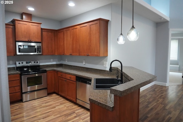 kitchen with decorative light fixtures, kitchen peninsula, appliances with stainless steel finishes, and sink