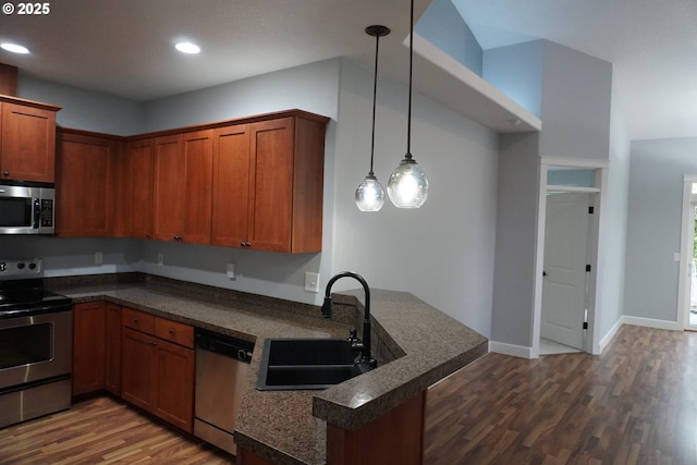 kitchen featuring dark hardwood / wood-style floors, pendant lighting, kitchen peninsula, sink, and stainless steel appliances