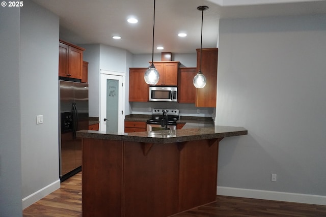 kitchen featuring dark hardwood / wood-style floors, kitchen peninsula, appliances with stainless steel finishes, and pendant lighting