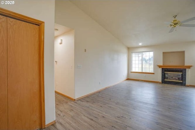 unfurnished living room with ceiling fan, hardwood / wood-style floors, lofted ceiling, and a tiled fireplace