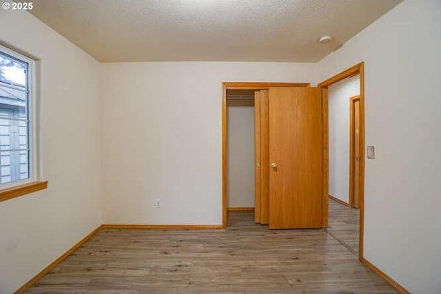 spare room with a textured ceiling, a wealth of natural light, and light hardwood / wood-style flooring