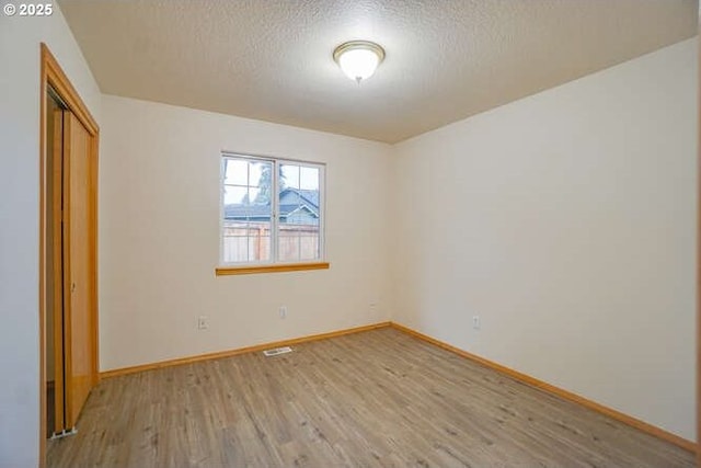 unfurnished bedroom with a textured ceiling, a closet, and light hardwood / wood-style floors