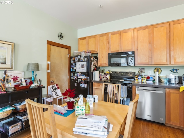 kitchen featuring dark countertops, wood finished floors, and black appliances