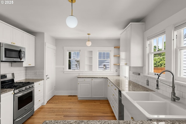 7505 SE 22nd Ave, Portland, OR 97202 - kitchen featuring stainless steel appliances, a sink, white cabinets, and pendant lighting