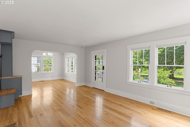 7505 SE 22nd Ave, Portland, OR 97202 - unfurnished living room with a chandelier, baseboards, light wood-type flooring, and arched walkways