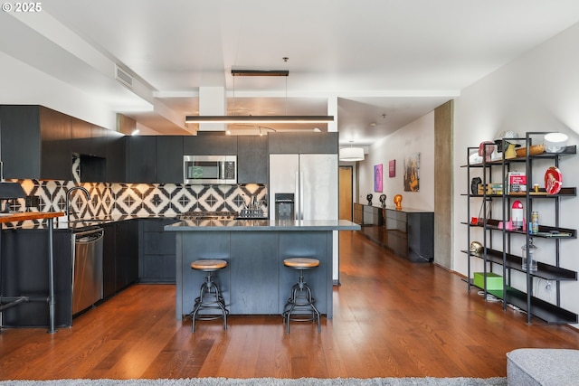 1221 SW 10th Ave Unit 410, Portland, OR 97205 - kitchen with appliances with stainless steel finishes, dark countertops, dark wood finished floors, decorative backsplash, and a kitchen island