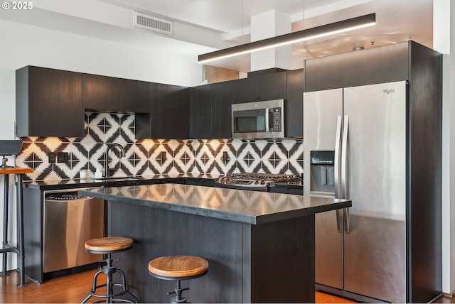 1221 SW 10th Ave Unit 410, Portland, OR 97205 - kitchen featuring stainless steel appliances, dark countertops, a kitchen island, and decorative backsplash